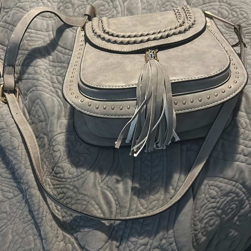 Small gray saddle crossbody bag with tassel.  This hands free back is cute.